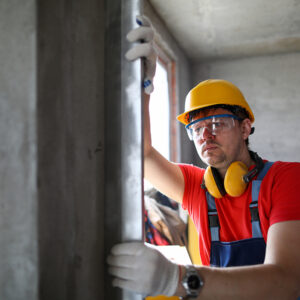 What wind speed are windows rated for in Florida - Builder in helmet measures level wall at window. Level is used to install door structures and windows. Measuring device used to control installation materials and structures in vertical planes